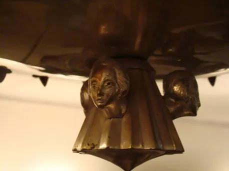 Lámpara de techo antigua con cabezas decorativas en el diseño.