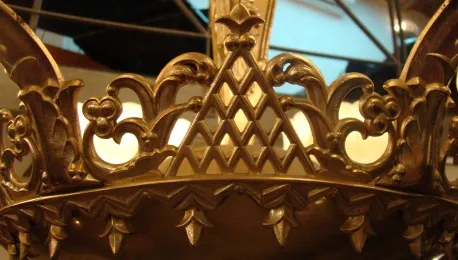 Lampada a sospensione antica con dettagli dorati su sfondo chiaro, circondata da un ambiente accogliente.