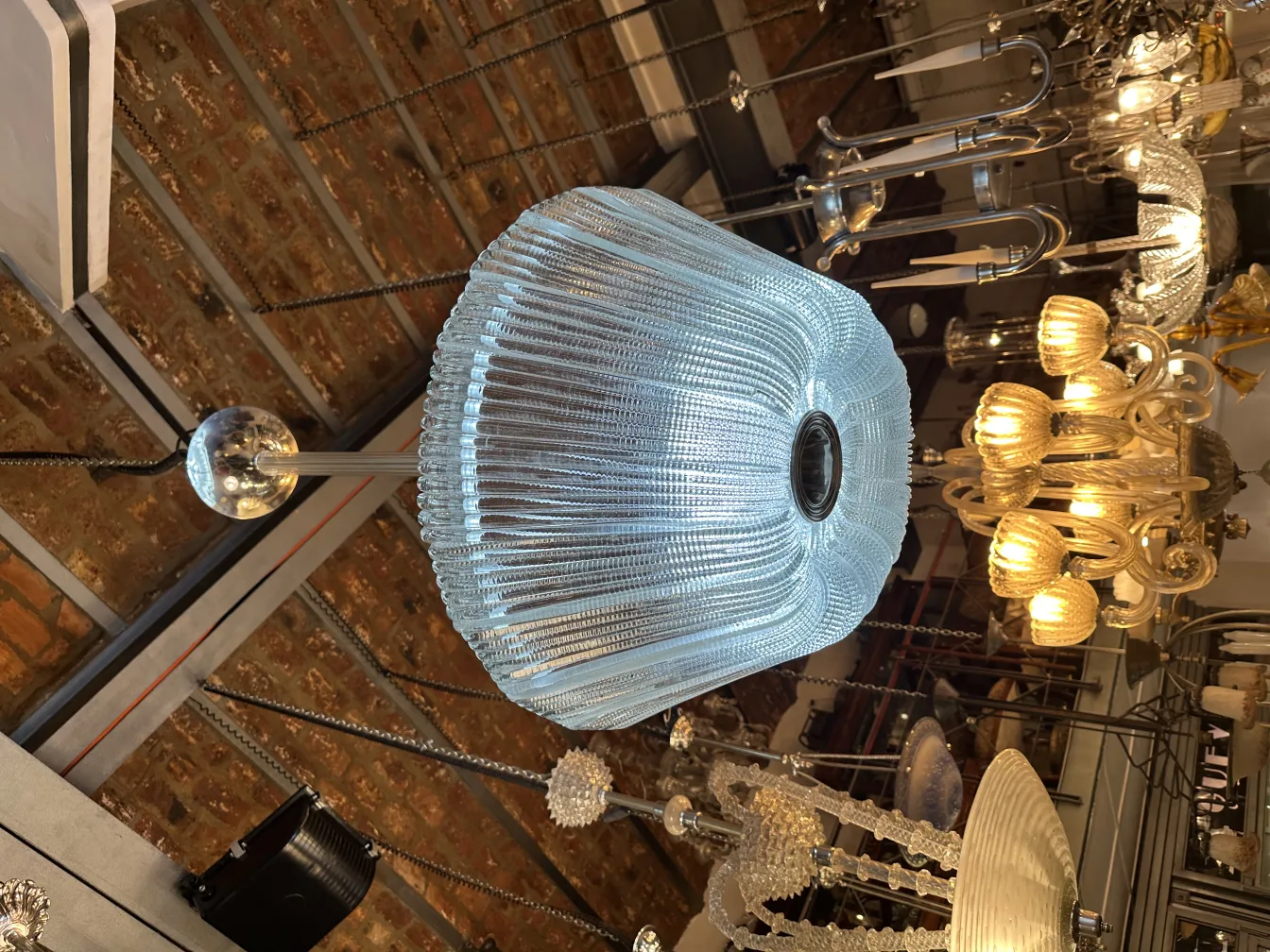 Antique hanging lamp made of glass with an elegant shape, warm lights in the background.