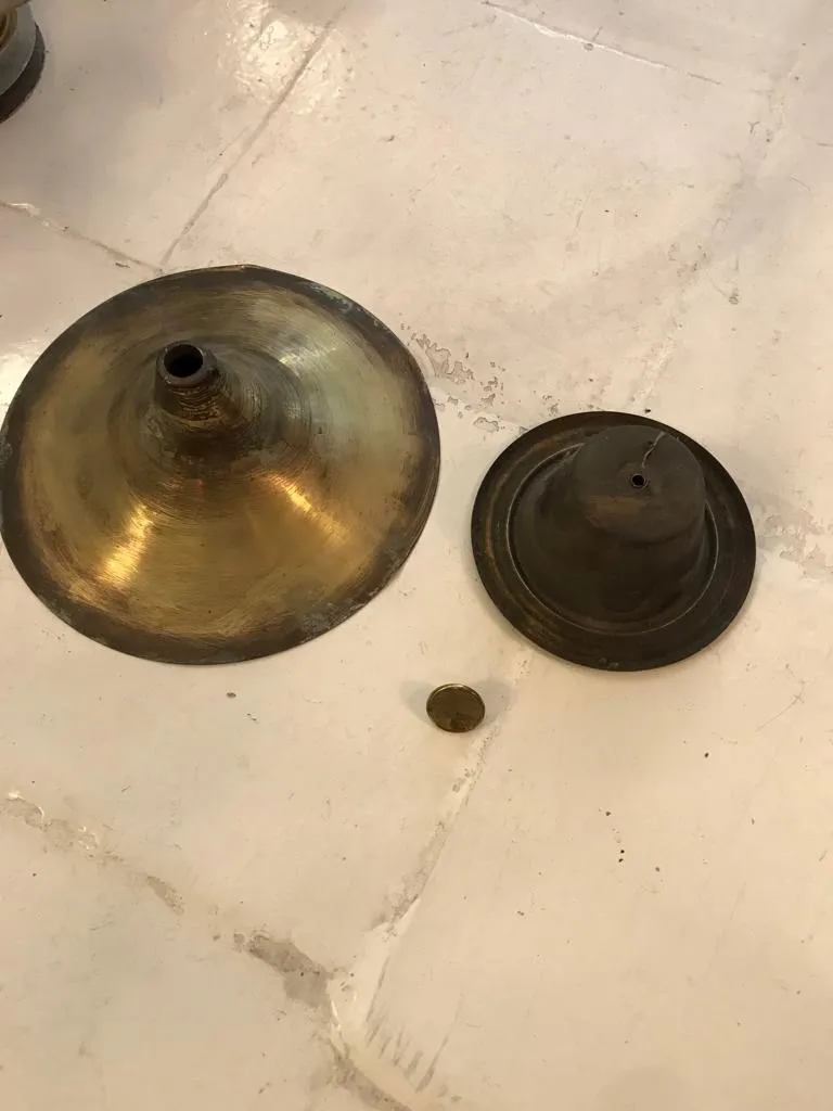 Componentes de una lámpara de techo antigua, bronce clásico, fondo claro.