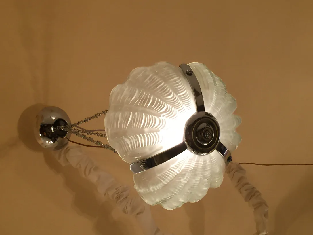 Lámpara de techo antigua con diseño de concha y luz cálida.