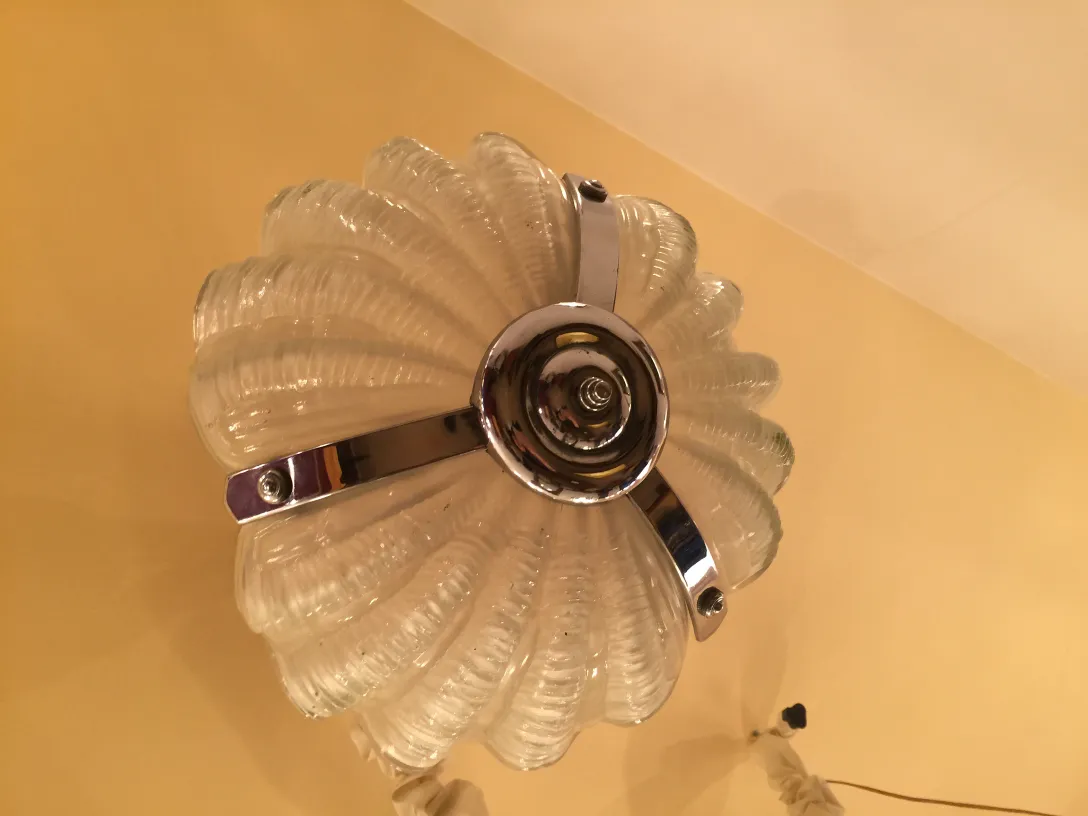 Lampada a sospensione antica con vetro ondulato e finitura lucida in un'atmosfera calda.