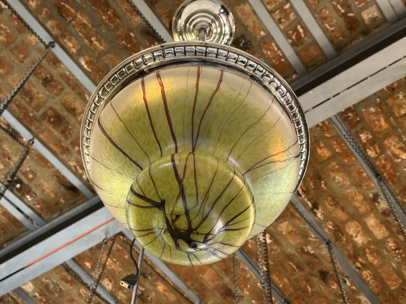 Lampada a sospensione antica verde con dettagli scuri, ambiente rustico.