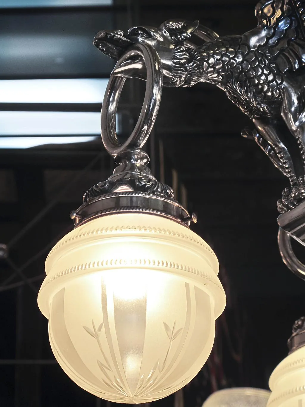 Lâmpada de teto antiga com um elegante globo opalino, apresentando detalhes decorativos em metal.