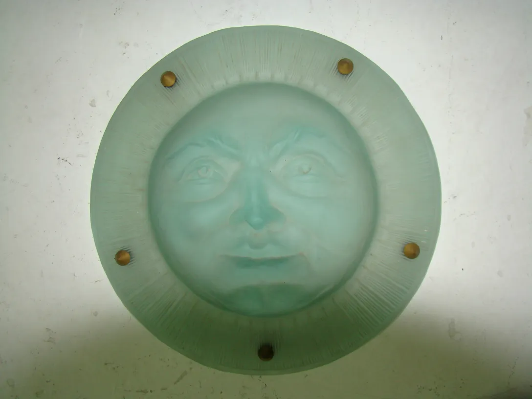 Antique hanging lamp featuring a carved smiling face, subtle ambiance.