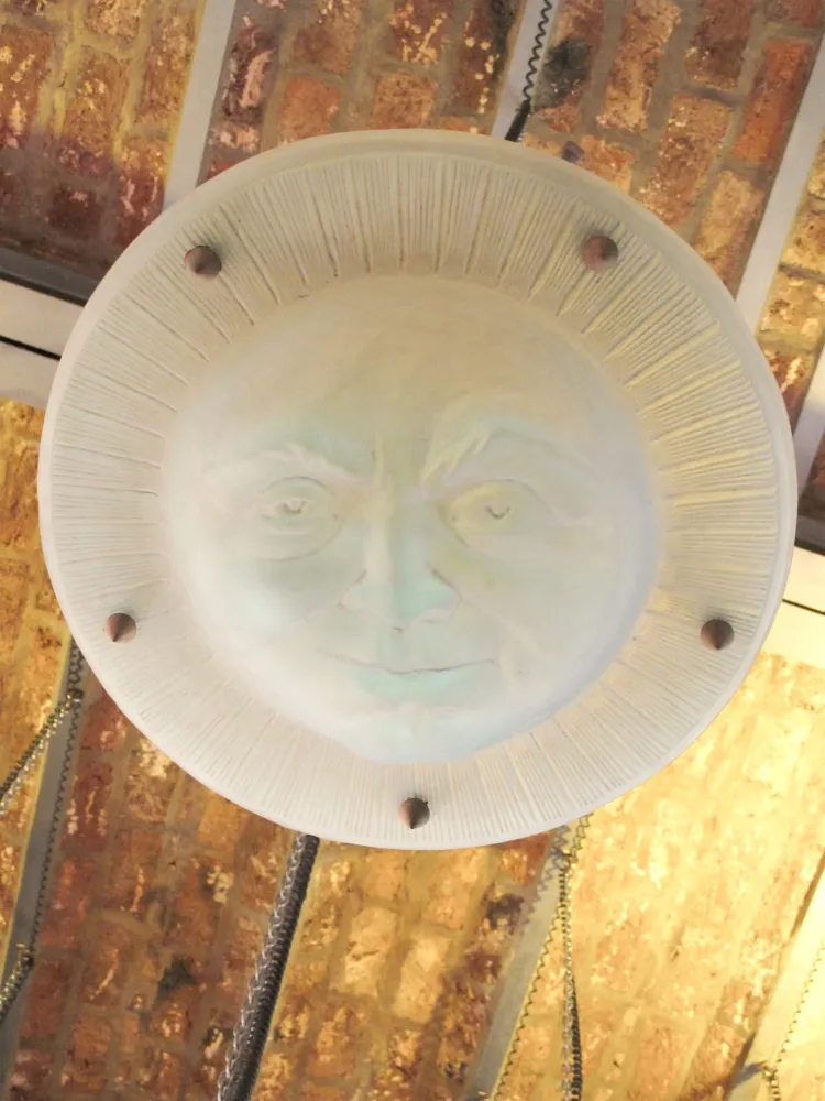 Antike Hängelampe mit Sonnenkopf in rustikalem Ambiente.