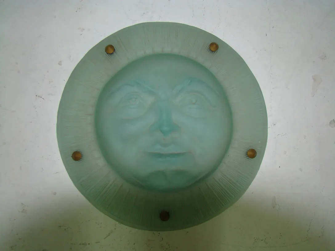 Antique hanging lamp featuring face designs and a round green base.
