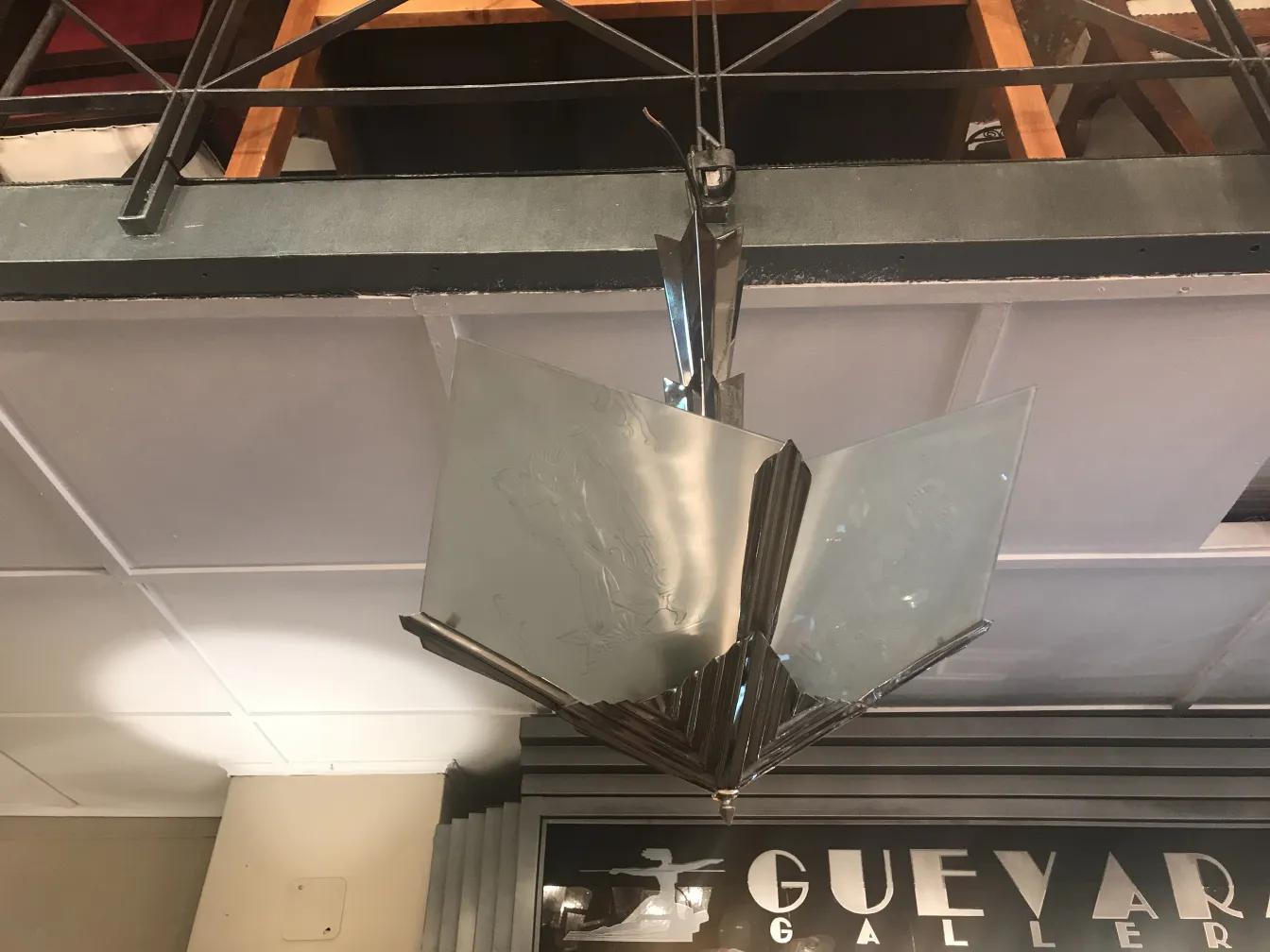 Lámpara de techo antigua con diseño de cristal brillante, colgado en un ambiente elegante con muebles de madera.