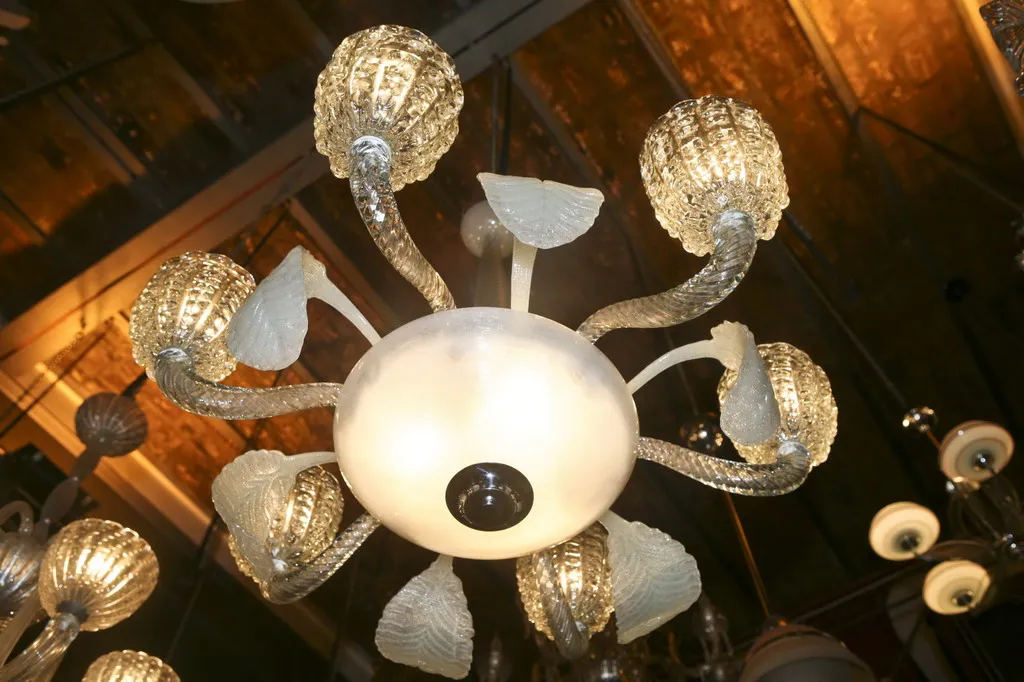 Lâmpada de teto antiga com estilo decorativo e braços curvados, iluminando um ambiente elegante.