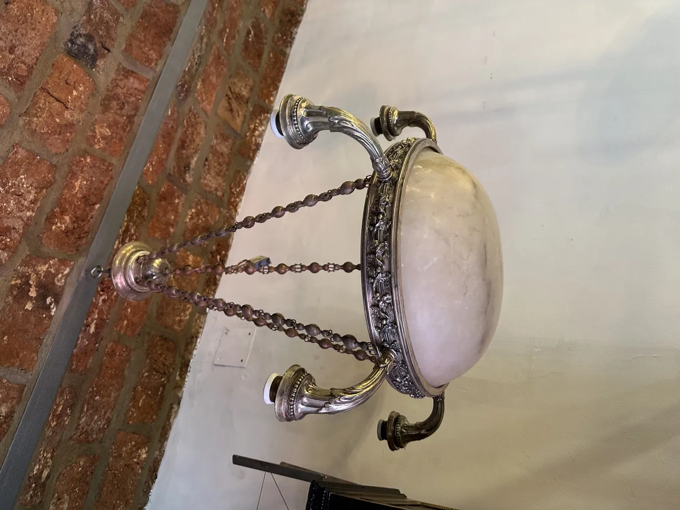 Lampada a sospensione antica con design elegante, adornata con catene, in un ambiente rustico.