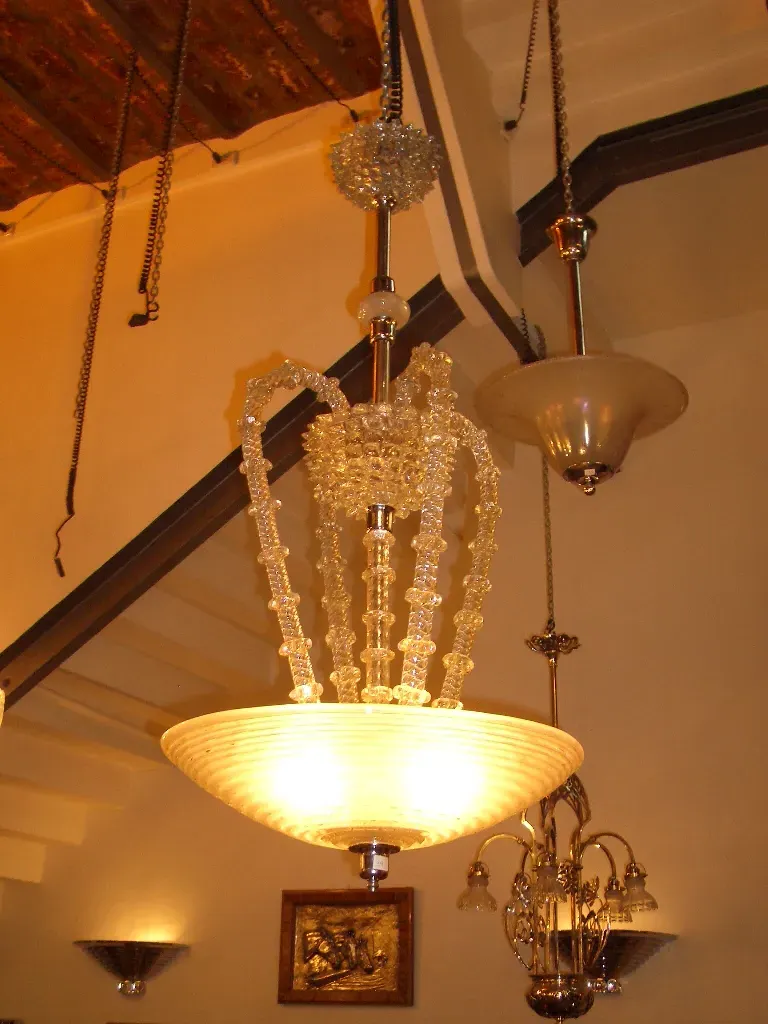 مصباح معلق قديم مزين بتفاصيل كريستالية، يضيء جوًا دافئًا.
