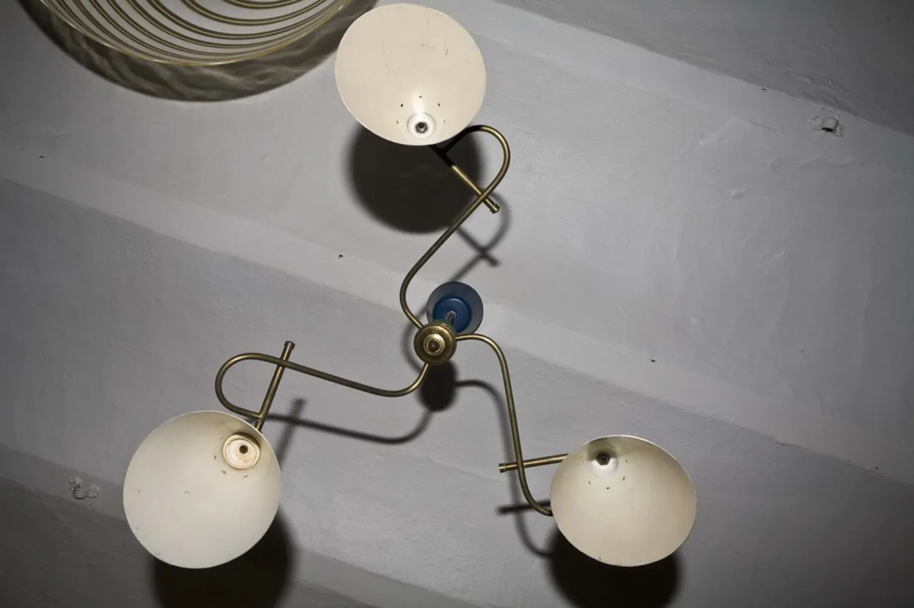 Lâmpada de teto antiga com dois braços em ambiente interno.