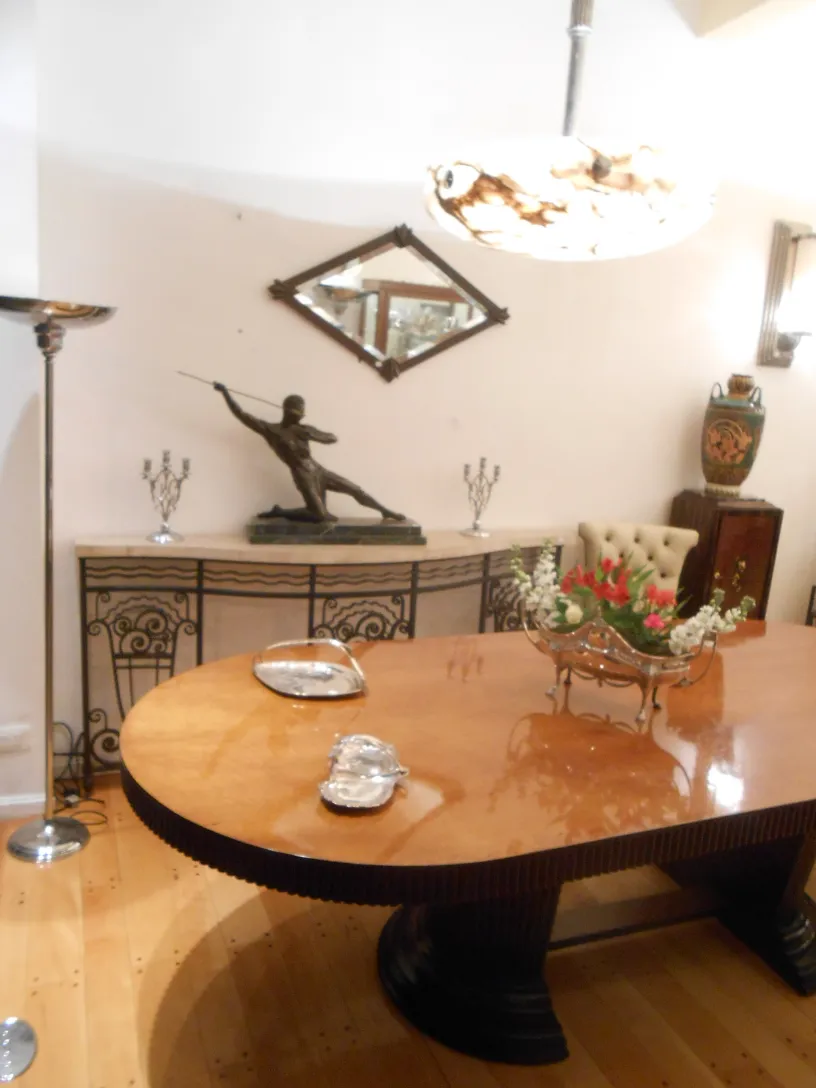 Lustre ancien illuminant une salle à manger élégante avec une table en bois brillant.