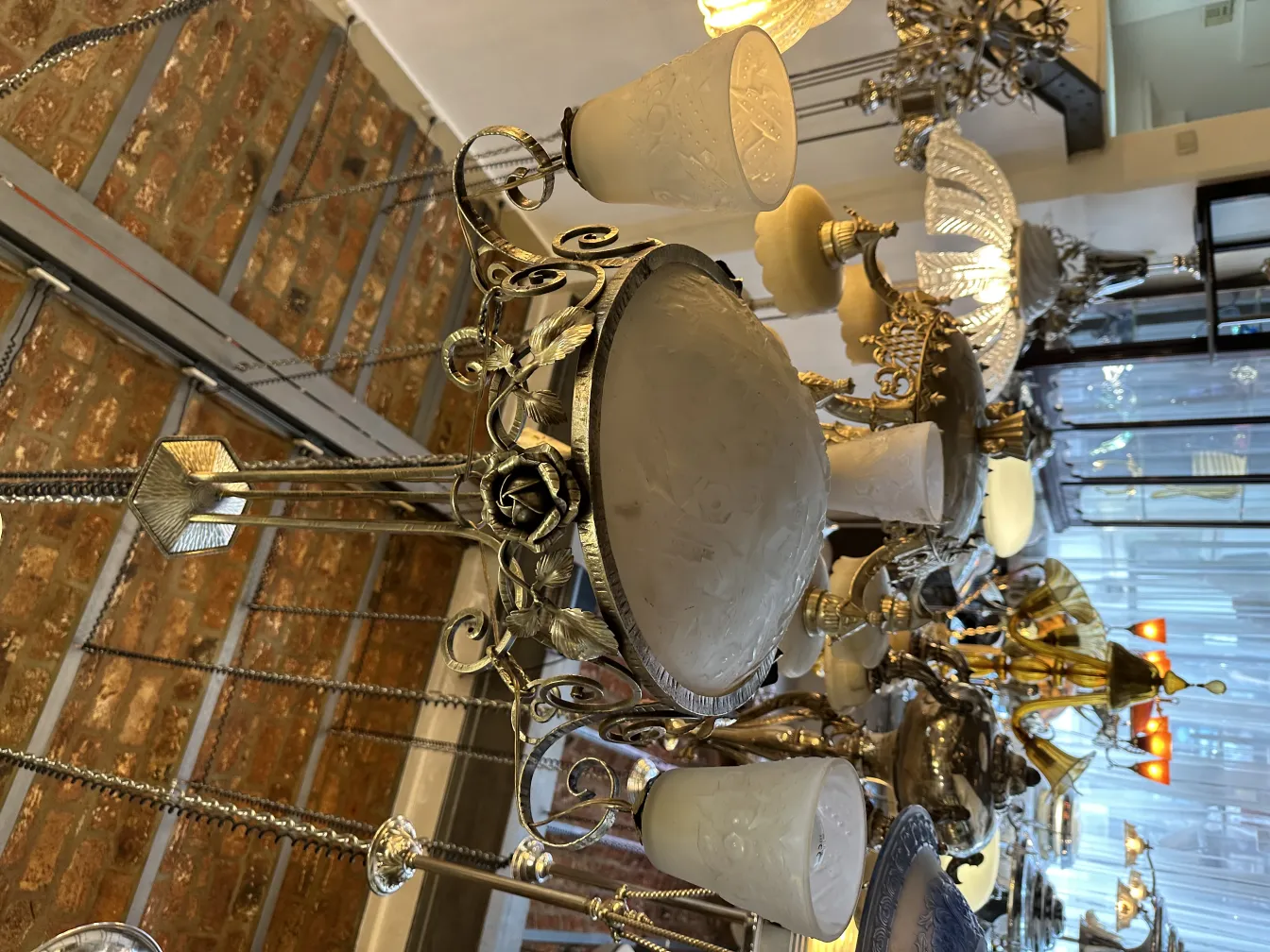 Lámpara de techo antigua con base decorativa y pantallas blancas en un ambiente elegante.