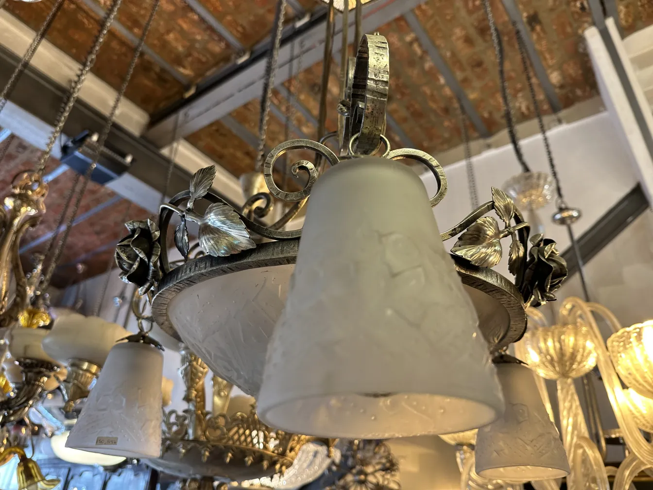 Antique hanging lamp featuring floral patterns and opal glass in a bright setting.