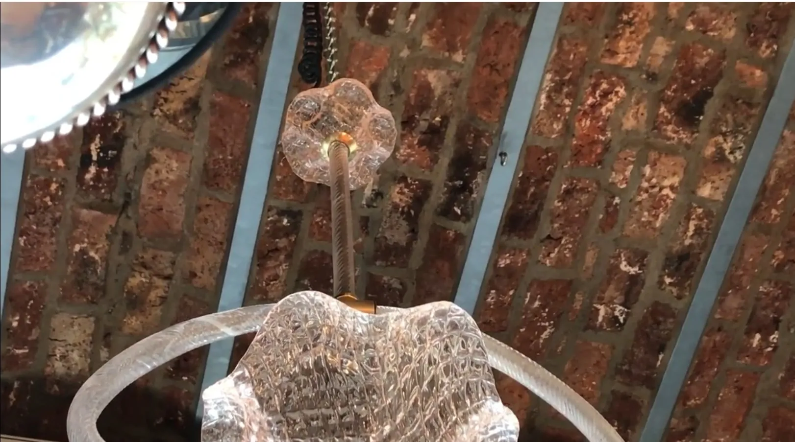 古老的吊灯，带有圆形细节和优雅的设计。裸露砖墙营造温馨氛围。