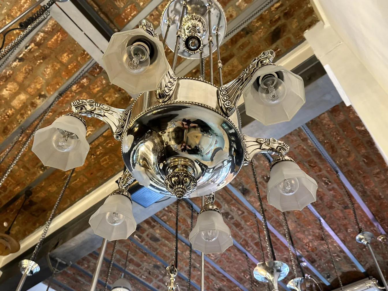 Lustre ancien avec abat-jours clairs et chandelier brillant.