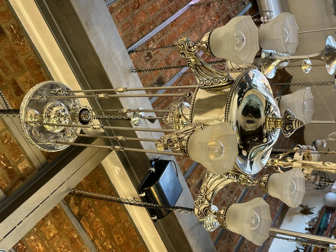 Lustre antique avec plusieurs lumières et abat-jours blancs, ambiance chaleureuse.