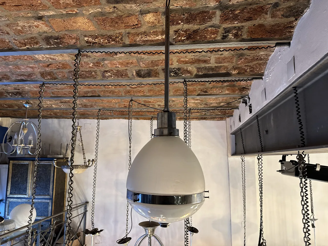 Lustre ancien dans un cadre rustique, avec des détails en chaîne.