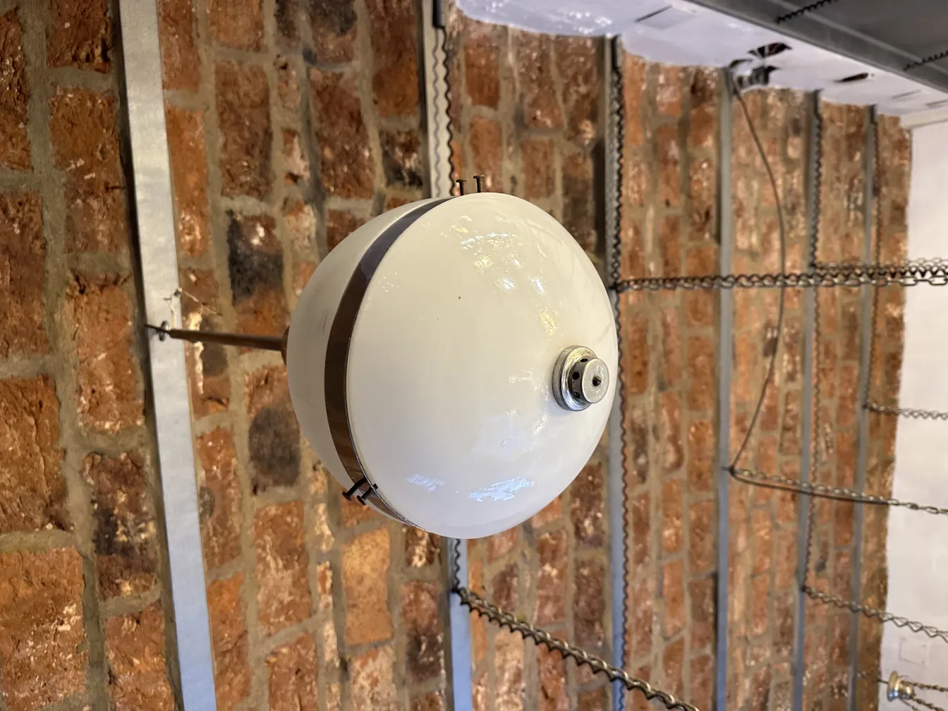 مصباح معلق قديم أبيض في غرفة ذات جدران من الطوب.