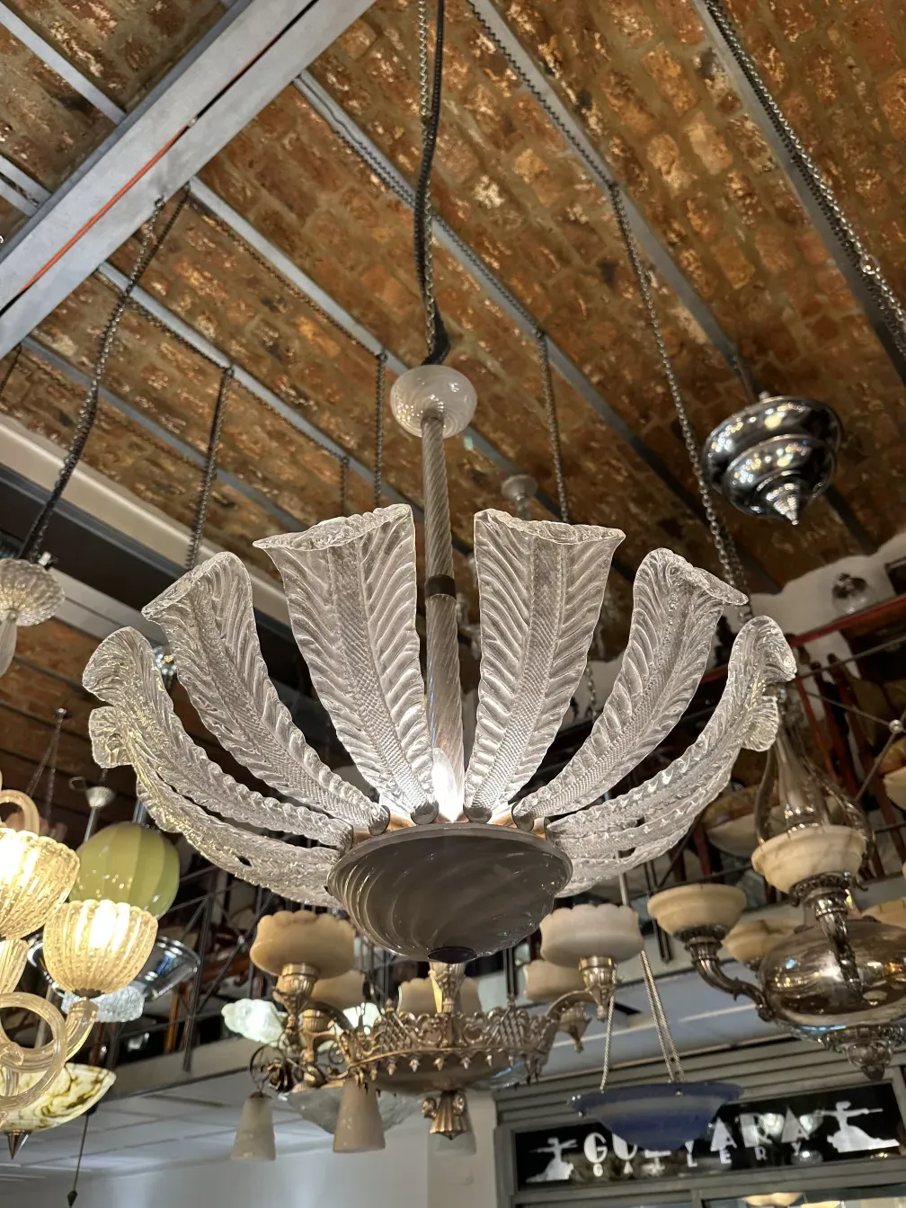 Lâmpada de teto antiga com detalhes decorativos em forma de folha, iluminando o ambiente.