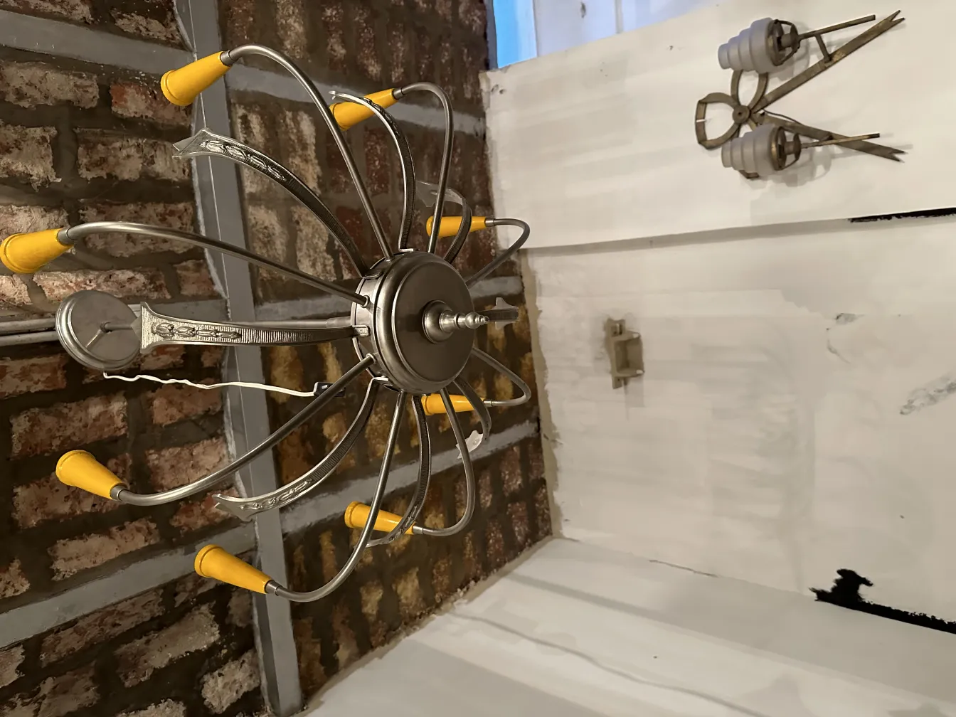 Lâmpada de teto antiga com braços de metal e detalhes brilhantes. Fundo de tijolos.