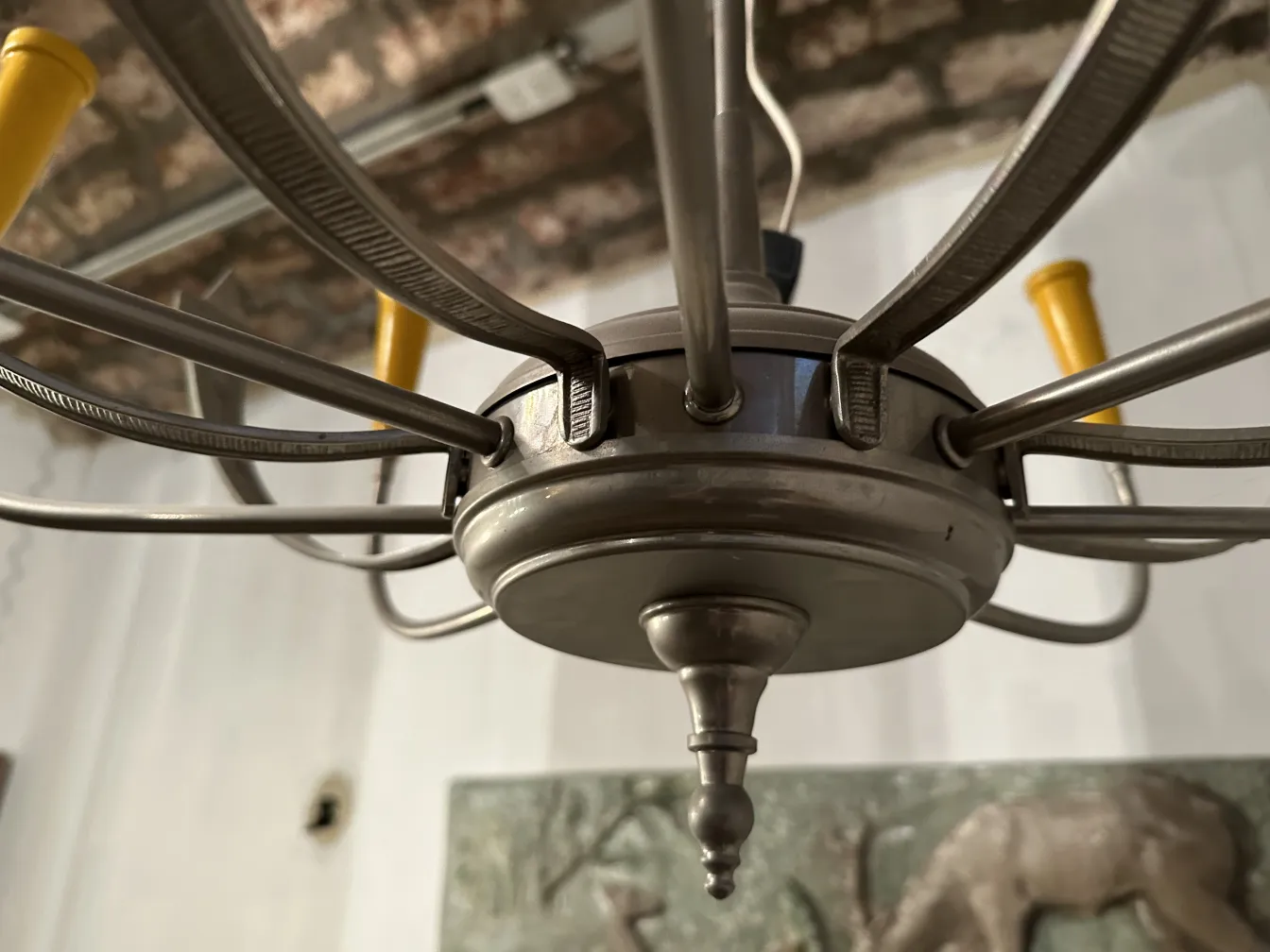 Lâmpada de teto antiga com varas douradas e detalhes decorativos, em um ambiente aconchegante