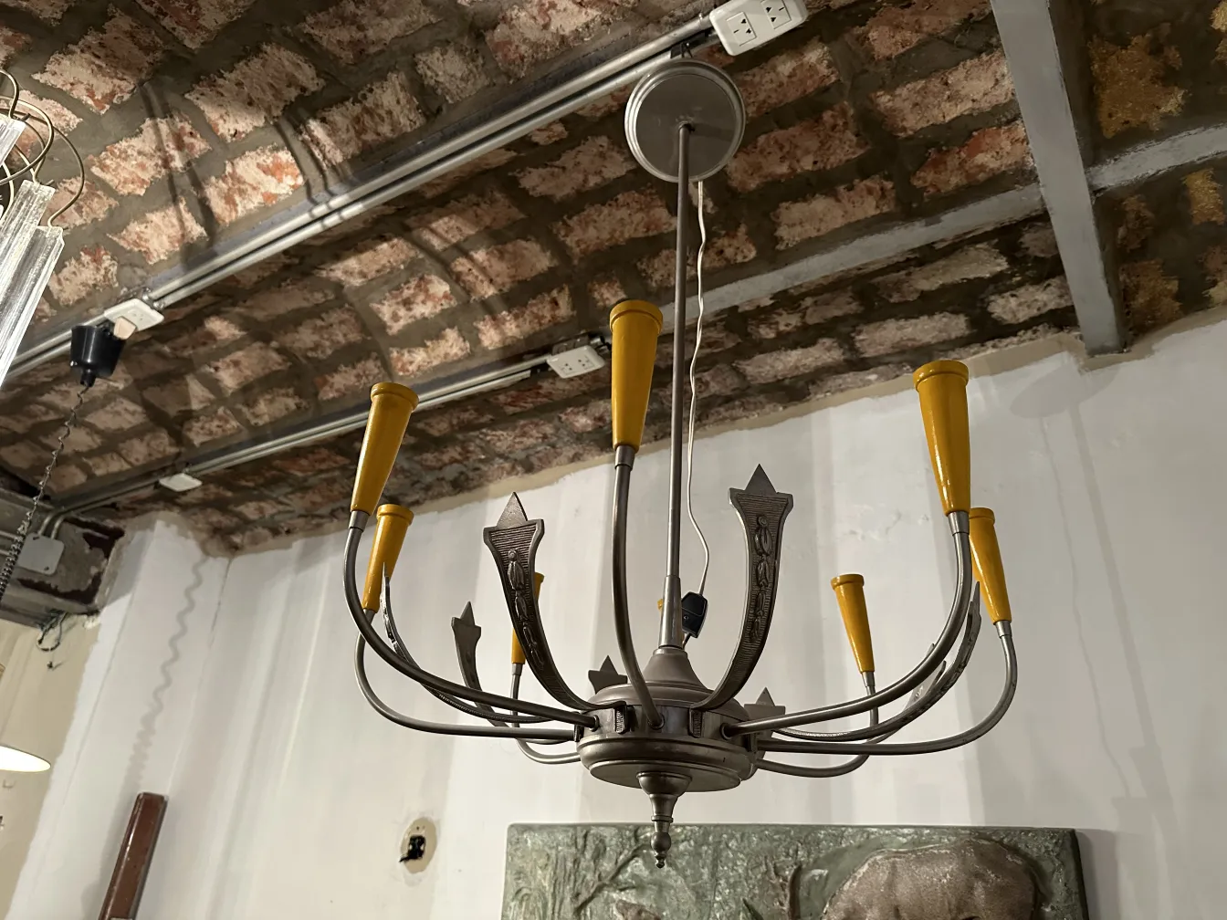 Luminária antiga de teto com braços amarelos em um ambiente rústico.