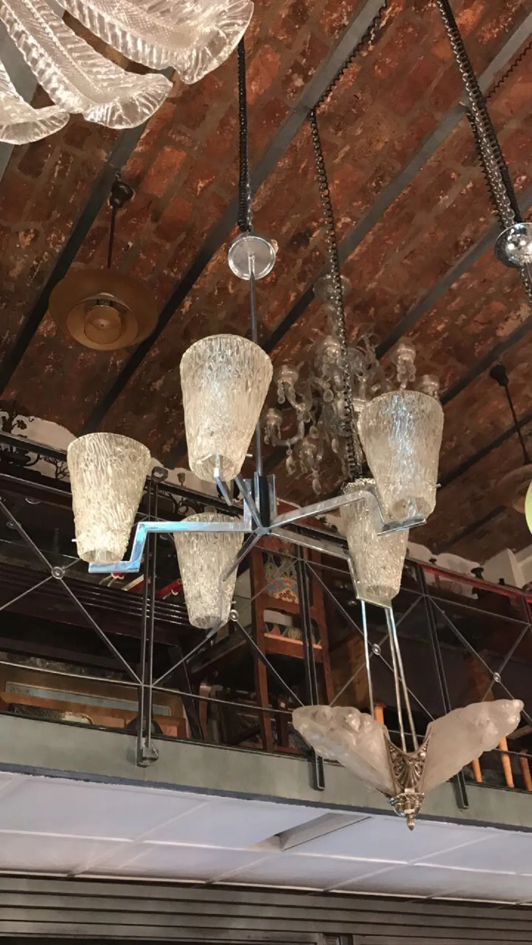 Antigua lámpara de techo con cinco pantallas y detalles elaborados en un ambiente acogedor.