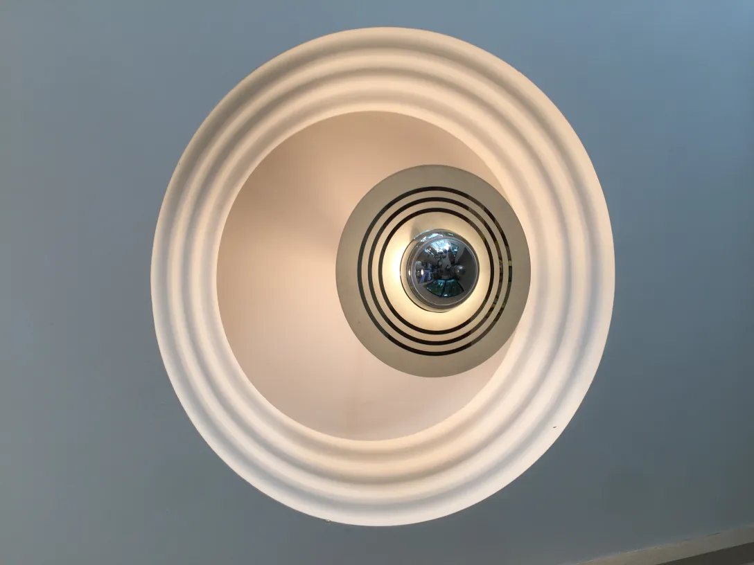 Lampada a sospensione antica con design circolare e riflessi.