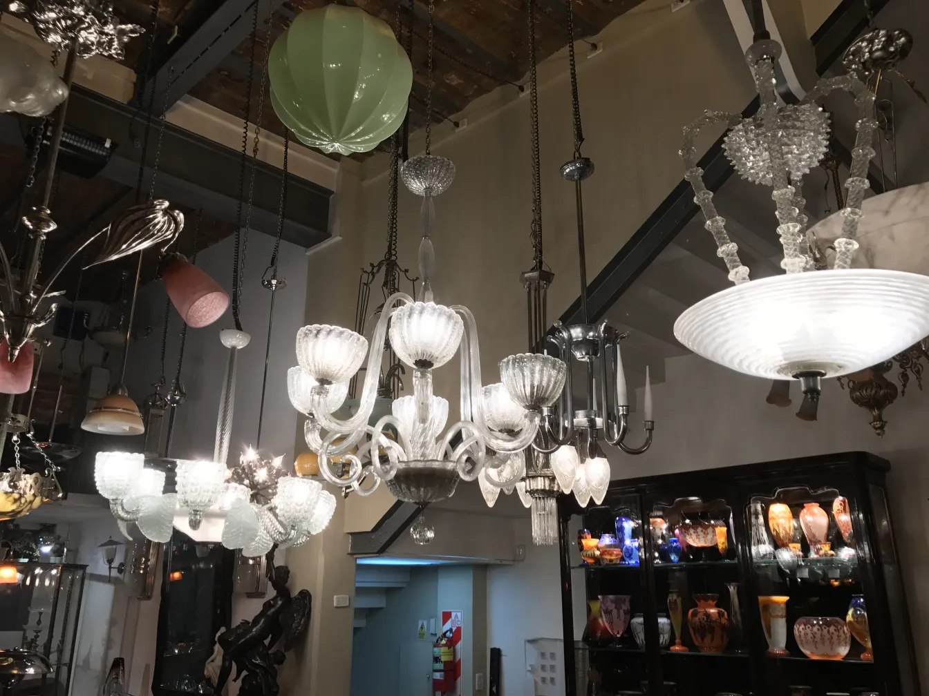 Lâmpada de teto antiga com detalhes ornamentais em cristal. Ambientada em uma galeria de antiguidades.