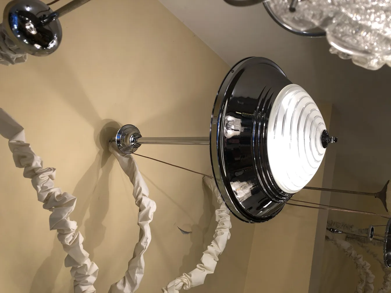 Lampada a sospensione antica con design lucido, in un ambiente neutro.