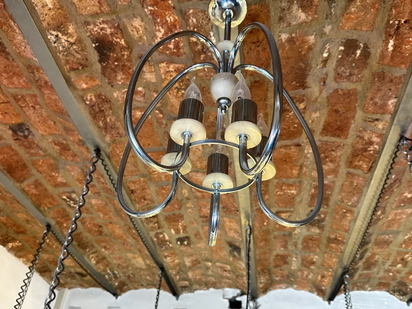 Antique hanging lamp with curves and lights in a rustic setting.