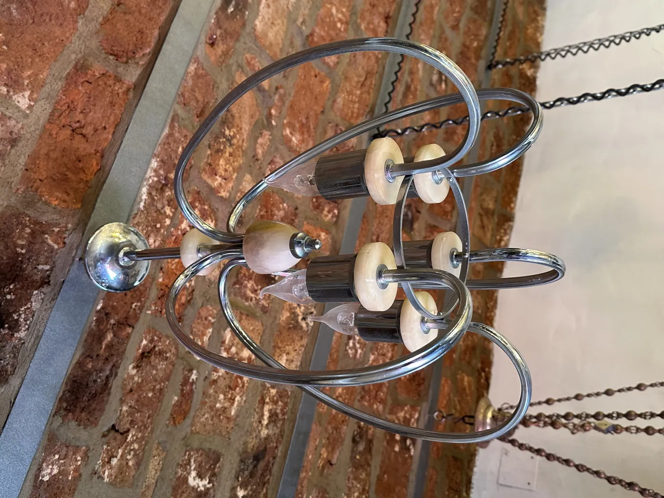 Lustre antique avec un design moderne, situé dans une pièce avec des murs en briques