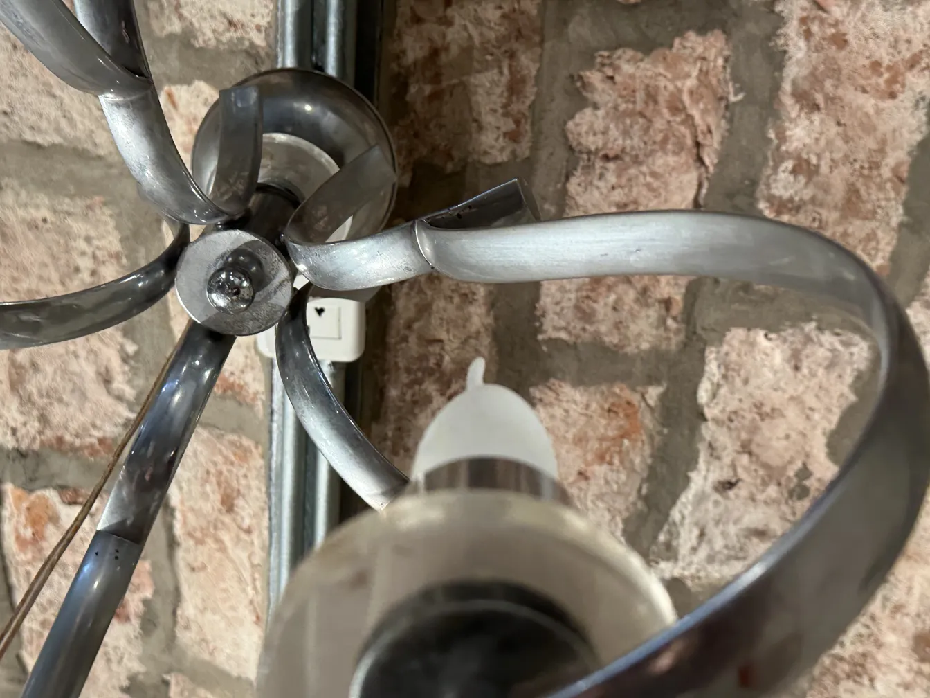 古董吊灯，带有弯曲的灯臂和装饰细节，放置在乡村环境中