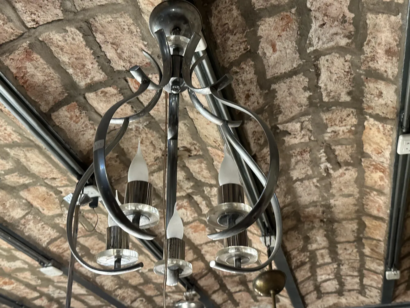 Antique hanging lamp with elegant details and bright lights in a rustic setting.