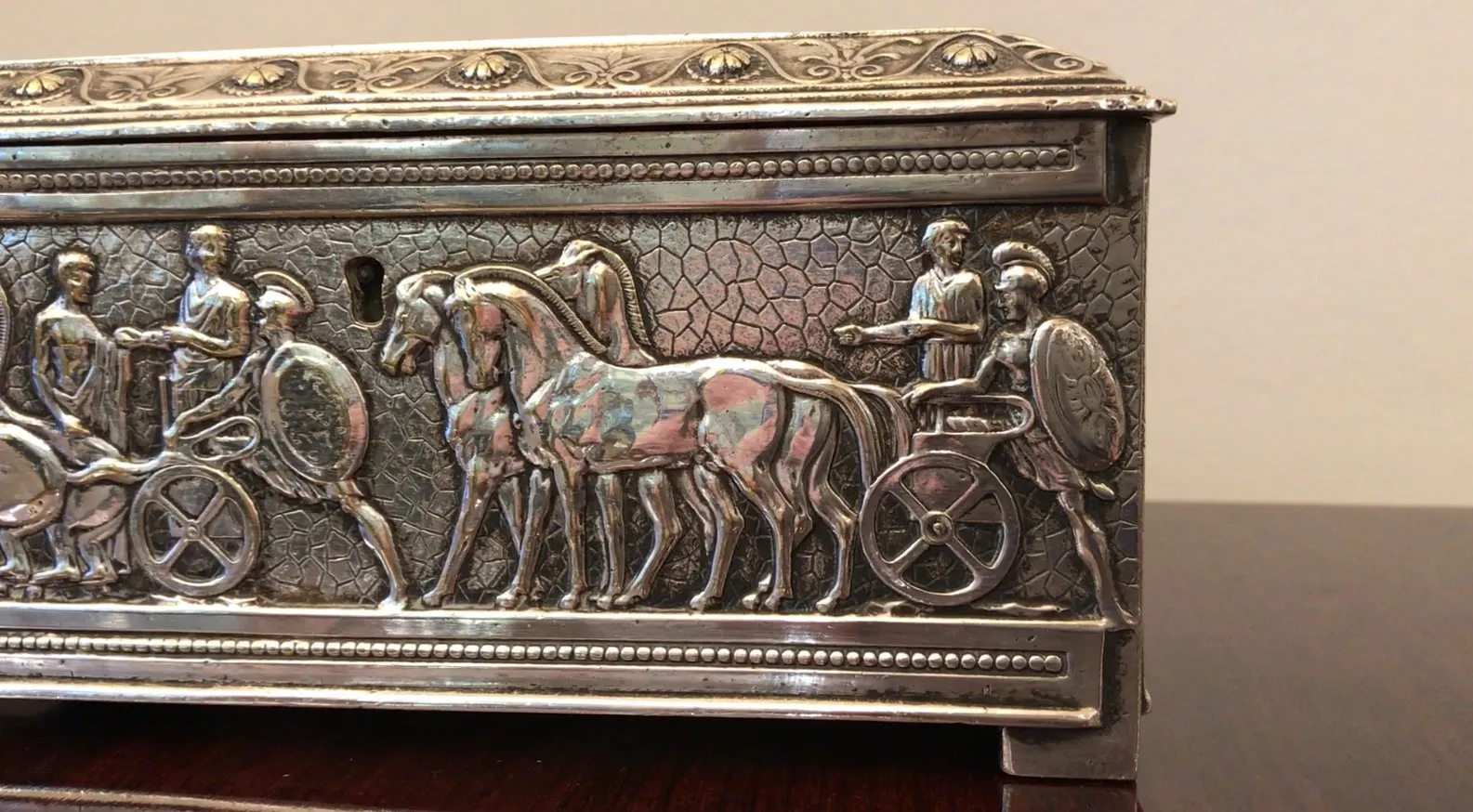 Boîte ancienne ornée de guerriers et de chevaux en relief, idéale pour l'exposition.