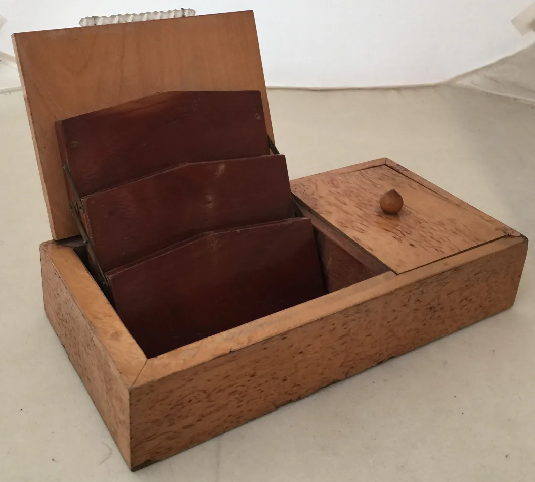 Caja antigua de madera con divisores internos y un pequeño compartimento.