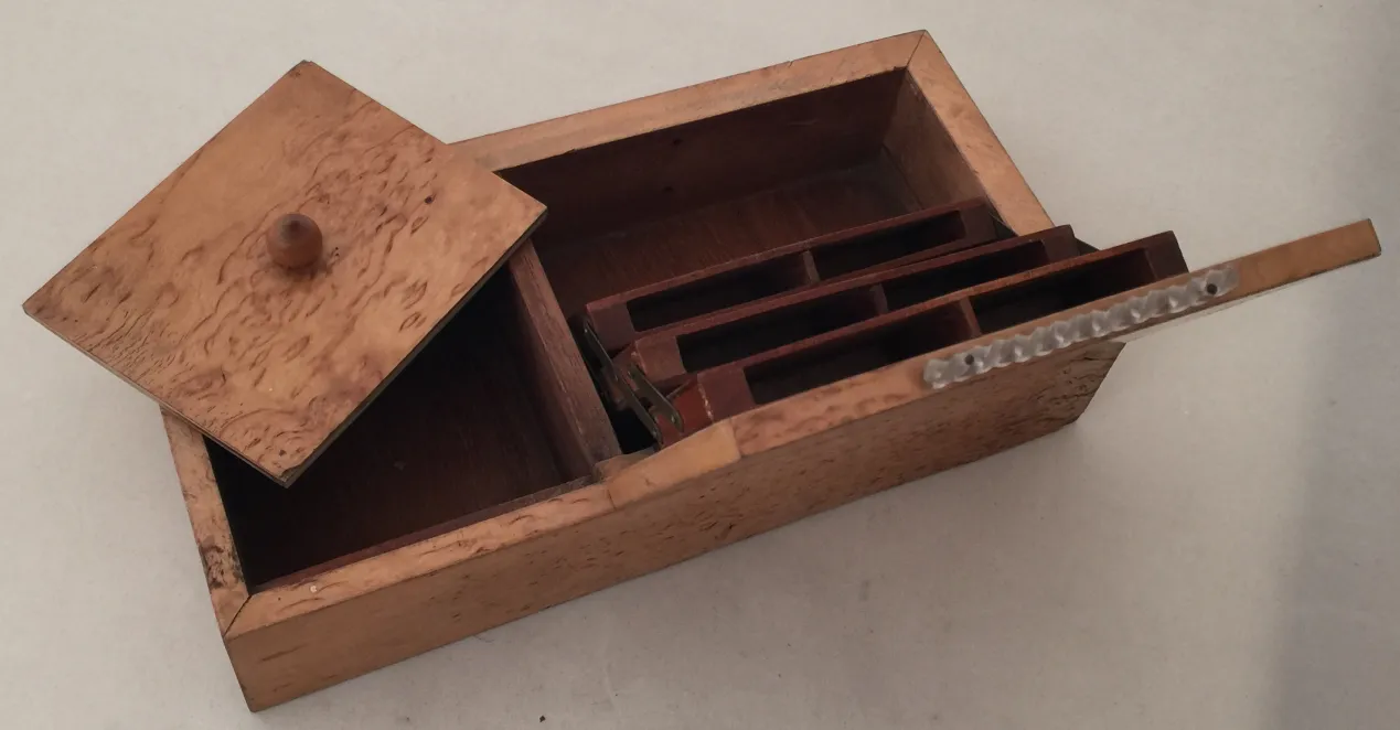 Caja antigua de madera con tapa y separadores interiores, ideal para organización.