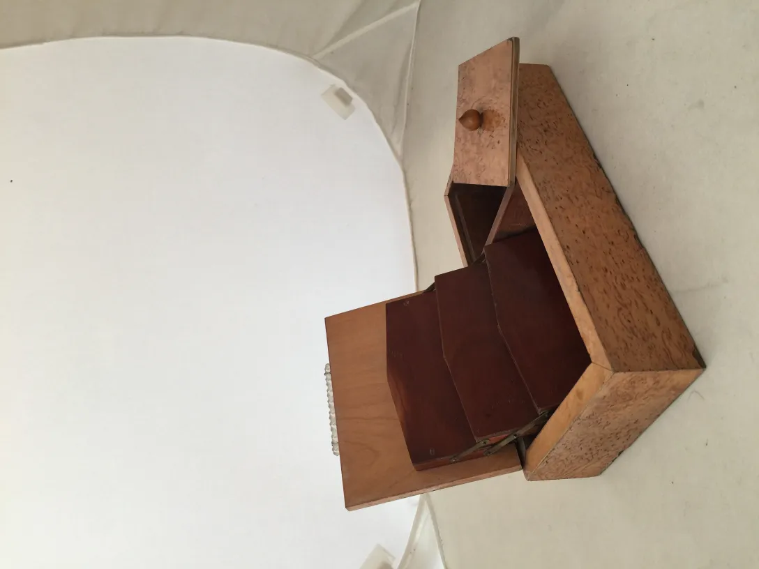 Boîte ancienne en bois avec compartiments internes dans un cadre neutre.