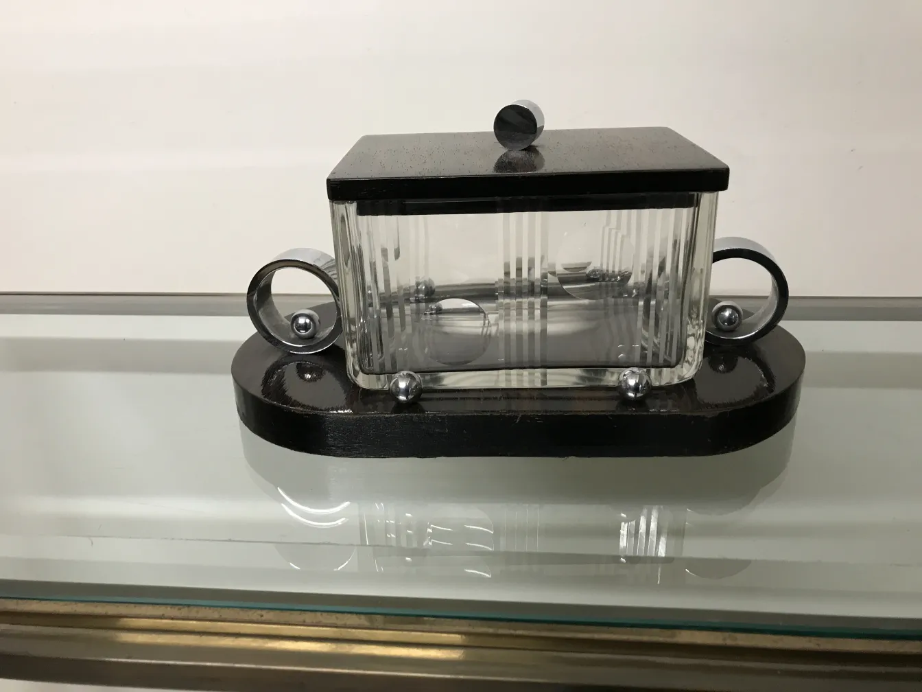 Caja antigua de vidrio con tapa y base negra, decorativa.