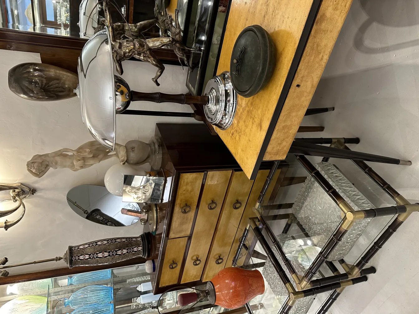 Caja antigua de madera con detalles decorativos, rodeada de antigüedades.