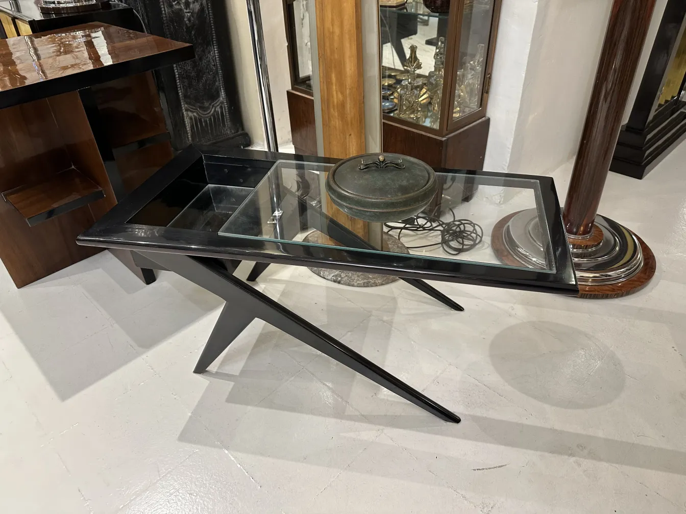 Caixa antiga com tampa de vidro em um ambiente retro. Inclui outros itens decorativos.