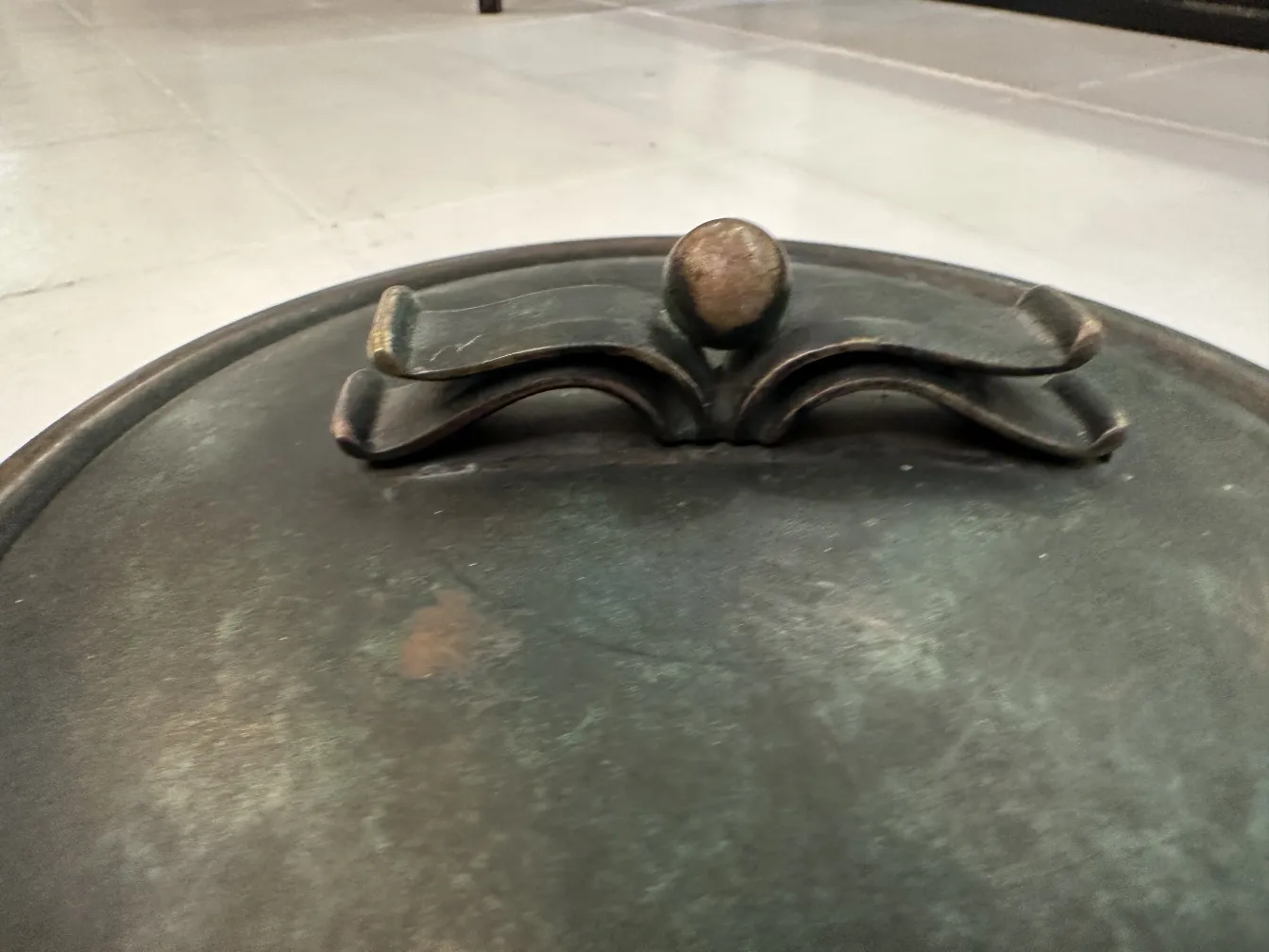 Boîte ancienne circulaire avec couvercle décoratif en couleurs sombres.