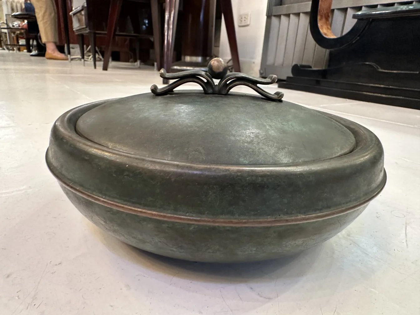 Caja antigua de forma redonda con tapa decorativa en un entorno clásico