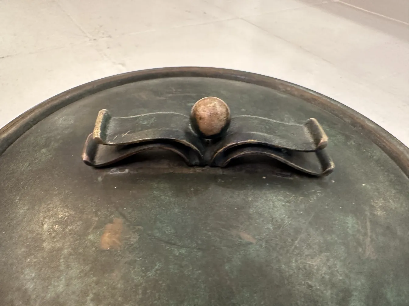 Boîte ancienne en métal avec un design unique, dotée d'un couvercle rond avec une poignée en haut.