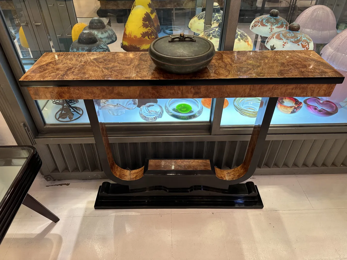 Decorative antique box with lid, placed on a table, surrounded by colorful glassware.