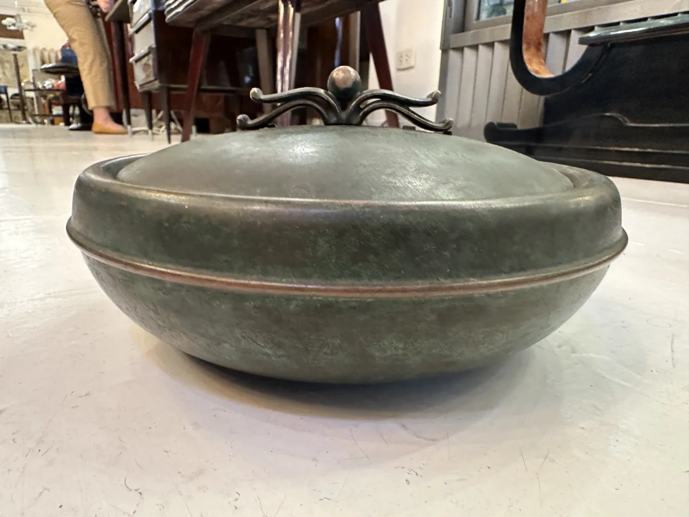 Boîte antique ronde avec couvercle décoratif dans un environnement d'antiquités.