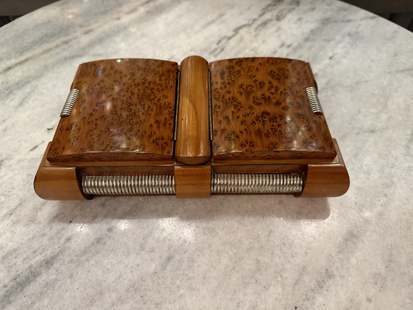 Antique wooden box with metal details, placed on a clear surface.
