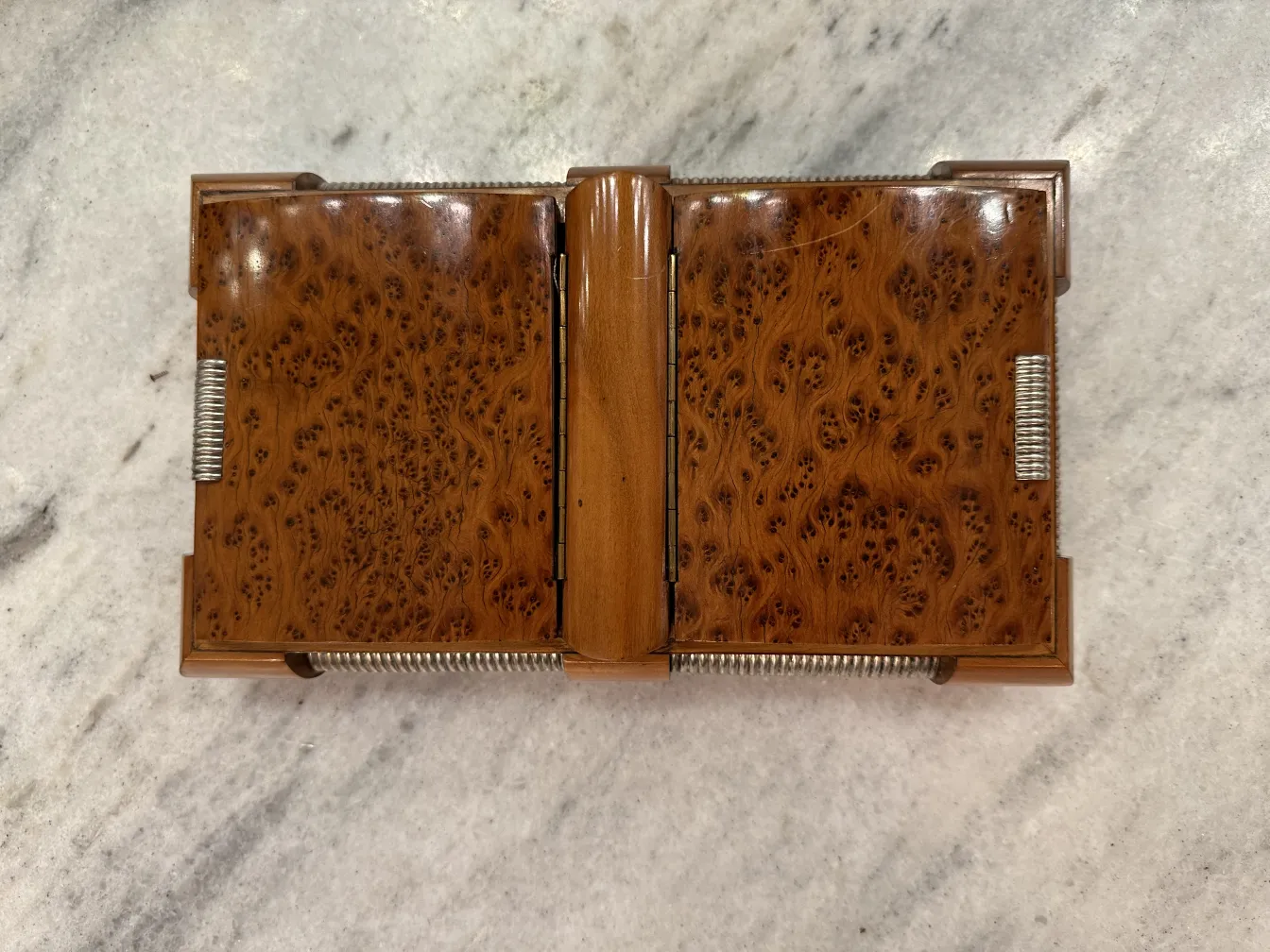 Boîte ancienne en bois avec des détails complexes, fermée sur une surface claire.